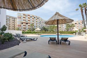 une terrasse avec des chaises et un parasol ainsi qu'une piscine dans l'établissement Hotel Best Terramarina, à La Pineda