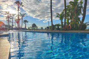 a large swimming pool with palm trees and the sun at Hotel Best Benalmadena in Benalmádena