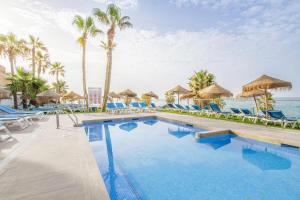 una piscina en un complejo con sillas azules y palmeras en Hotel Best Benalmadena, en Benalmádena