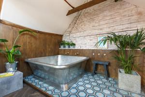 Shirehall Apartments في هولت: حوض استحمام في غرفة مع اثنين من النباتات الفخارية