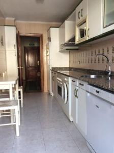 a kitchen with white cabinets and a sink at Apartamento en la Playa de Somo. in Somo