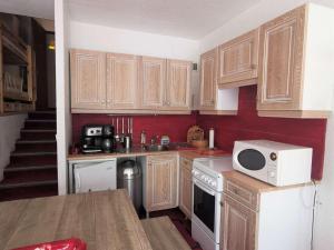 a kitchen with wooden cabinets and a white microwave at Studio cabine 4 pers. La Mongie, centre station, près des pistes - FR-1-404-333 in La Mongie