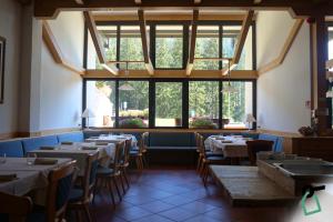 - une salle à manger avec des tables, des chaises et des fenêtres dans l'établissement HOTIDAY Residence Campiglio, à Madonna di Campiglio
