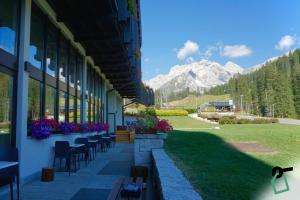 a building with tables and chairs and mountains in the background at HOTIDAY Residence Campiglio in Madonna di Campiglio