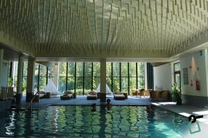 a hotel lobby with a swimming pool with a large ceiling at HOTIDAY Residence Campiglio in Madonna di Campiglio