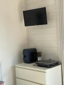 a television on a wall next to a table with a laptop at Il CASALETTO di Laura in Fiumicino
