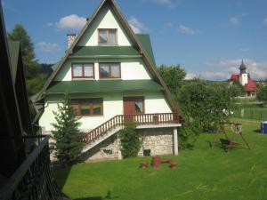 ein großes Haus mit grünem Dach und Garten in der Unterkunft Hacjenda - Apartamenty i Pokoje Gościnne in Czarna Góra