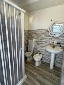 een badkamer met een wastafel, een toilet en een spiegel bij Il CASALETTO di Laura in Fiumicino