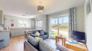 a living room with a couch and a tv and a kitchen at G07 Tweenbanx, Riviere Towans in Hayle