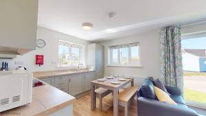 a kitchen and living room with a couch and a table at G07 Tweenbanx, Riviere Towans in Hayle +10 photos