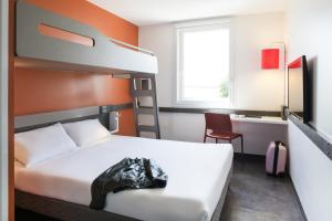 a hotel room with a bed and a desk at ibis budget Aéroport Lyon Saint Exupéry in Saint-Exupéry