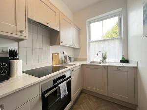a kitchen with white cabinets and a sink and a window at 2-Bed Victorian Elegance in Chester