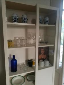 a cabinet filled with glasses and a blue bottle at Del Nobile Apartment in Turin