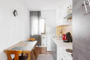 eine weiße Küche mit einem Holztisch und Stühlen in der Unterkunft MaliDu Apartment Krefeld Düsseldorf in Krefeld