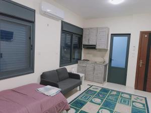 a bedroom with a bed and a chair and a kitchen at For Women Only - للنساء فقط in Umm el ‘Amad