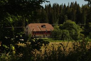 ein Haus mit rotem Dach auf einem Feld in der Unterkunft Le Logis de Pimpi in Lamoura