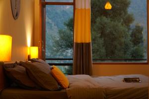 1 dormitorio con cama y ventana grande en Firefly Hostel en Manāli