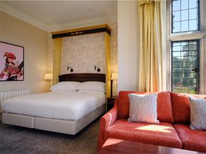 1 dormitorio con 1 cama y 1 sofá en Delta Hotels by Marriott Breadsall Priory Country Club, en Derby