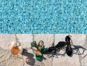 a pair of shoes and a pair of glasses next to a swimming pool at Holiday home Blue Sky in Zaostrog