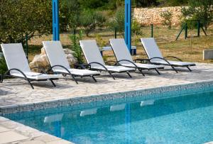 a row of lounge chairs next to a swimming pool at Holiday home Blue Sky in Zaostrog