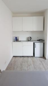 eine weiße Küche mit weißen Schränken und Holzböden in der Unterkunft Excellent Apartment M&L in Wien