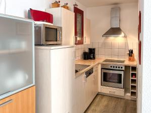 a kitchen with white cabinets and a microwave at Dünenblick Wohnung 37 in Boltenhagen