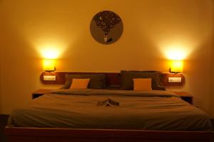 a bedroom with a bed with two lights on the wall at Firefly Hostel in Manāli