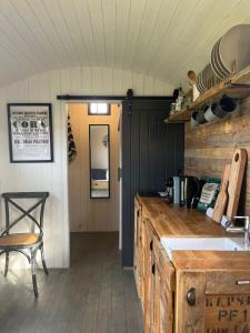 a kitchen with a counter and a table and a chair at Shepherds Huts in Kidlington