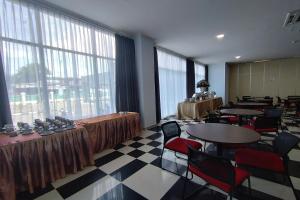 Habitación con mesas, sillas y ventanas grandes. en Hotel Sutha Inn en Jambi