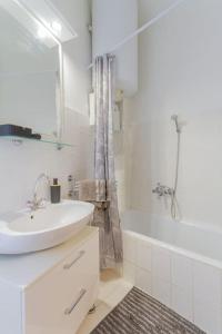 a white bathroom with a sink and a bath tub at Poppy's Home by the Danube by NW in Budapest