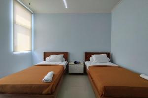 two beds in a small room with at Hotel Sutha Inn in Jambi