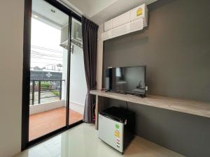 a living room with a tv and a balcony at Kefir Phuket in Kamala Beach