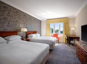 ダービーにあるDelta Hotels by Marriott Breadsall Priory Country Clubのベッド2台、薄型テレビが備わるホテルルームです。