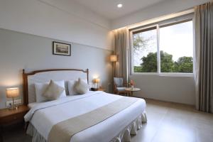 een slaapkamer met een groot bed en een groot raam bij juSTa Rudra Resort & Spa in Kolad