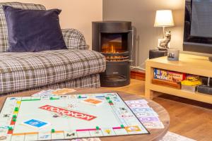 a living room with a fireplace and a board game on a table at The Jaw Barn in Milngavie