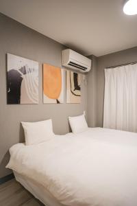 a bedroom with a large white bed and a air conditioner at 殿堂 in Tokyo