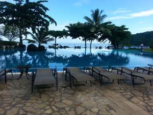 a pool with tables and chairs next to a body of water at Toupidek-sur-la-Plage in Arue