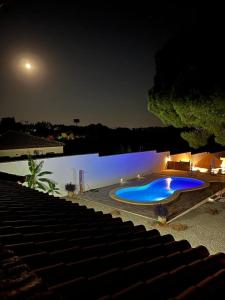 a large blue swimming pool at night next to a lake at CÁDIZ -TIPI en Chiclana de la frontera, España in Chiclana de la Frontera