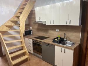 een keuken met witte kasten, een wastafel en een ladder bij Apartments Malivojevič in Žirovnica +34 foto's
