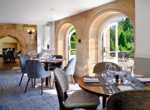 ダービーにあるDelta Hotels by Marriott Breadsall Priory Country Clubのテーブルと椅子、アーチ道のあるレストラン