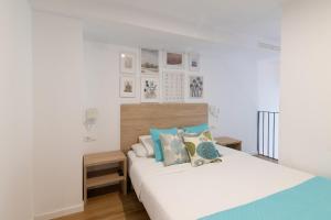 a bedroom with a bed with white sheets and blue pillows at DormForYou Alameda 12 Apartment in Valencia