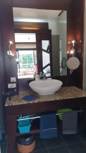 La salle de bains est pourvue d'un lavabo et d'un grand miroir. dans l'établissement Toupidek-sur-la-Plage, à Arue