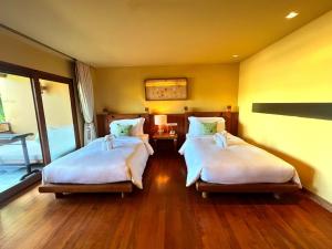 a room with two beds in a room at Deva Beach Resort Samui in Choeng Mon Beach