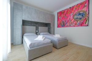 a bedroom with two beds and a painting on the wall at BergamoCityCenter 01 in Bergamo