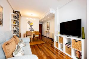 a living room with a couch and a flat screen tv at Atico Martina Centro in Gijón