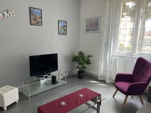 a living room with a tv and a purple chair at Appartement T3 très calme - Le Bartholdi - Centre de Colmar in Colmar