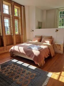 una camera con un grande letto in una stanza con finestre di La Maison Pelloquin a Bernières-sur-Mer