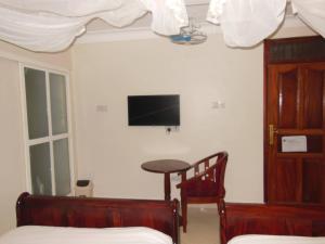 a bedroom with a bed and a tv on the wall at Psalms Motel in Entebbe