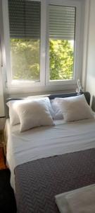 1 cama con almohadas blancas frente a una ventana en Apartman MINNA2, free parking, en Osijek