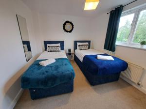Milton 5BR House with free parking, 3.5 Bathrooms ideal for CONTRACTORS & WEEKEND stays في Broughton: غرفة نوم بسريرين ذات أغطية زرقاء ونافذة